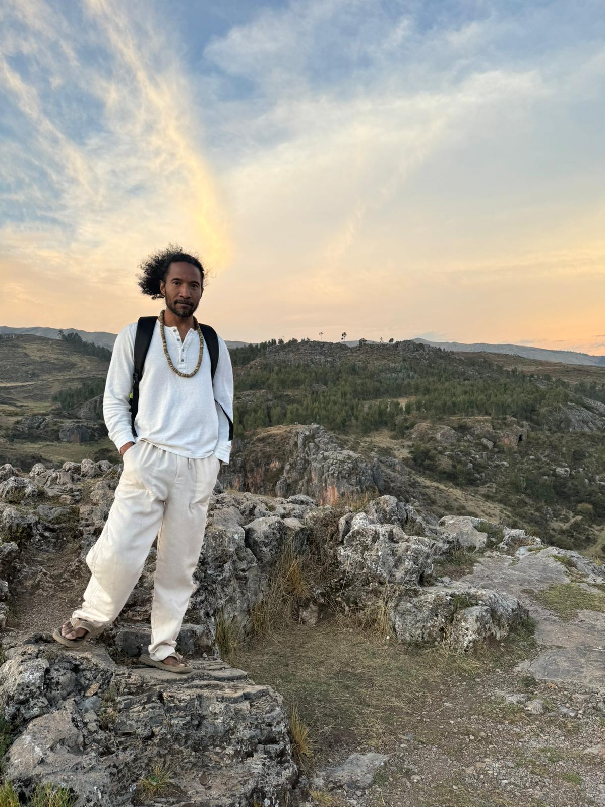 Patrick Wingate standing on a rocky ridge at sunset in the mountains